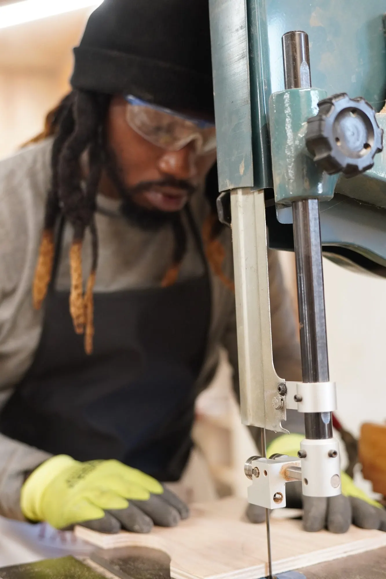 Maker in safety glasses guiding a stool template through the band saw