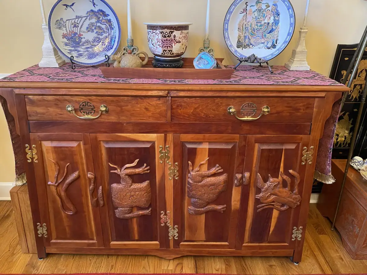 Hardwood cabinet with relief-carved dragon doors, brass pulls, and a patterned runner