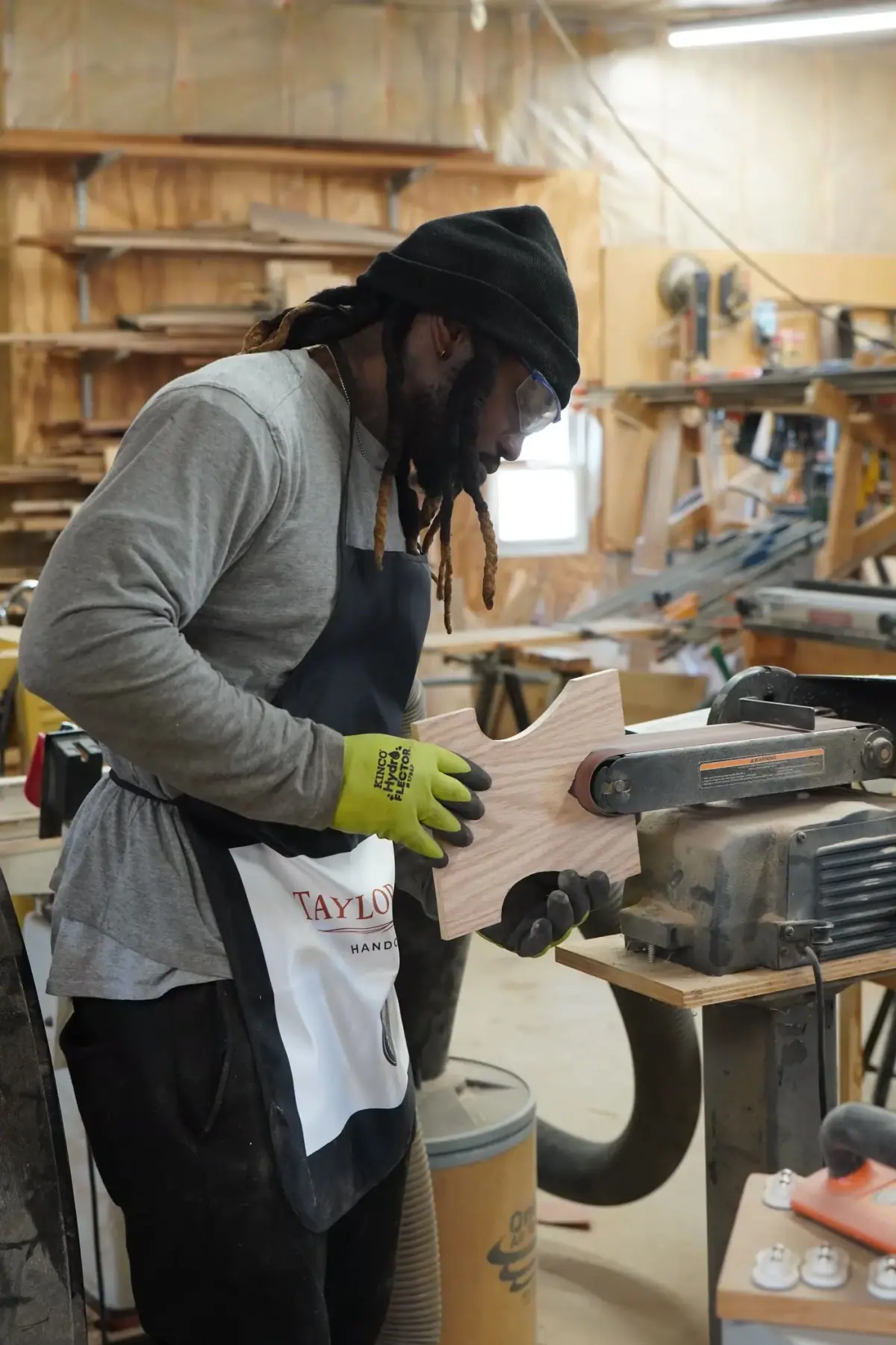 Dan shaping a stool leg on the belt sander at Taylor & Grain