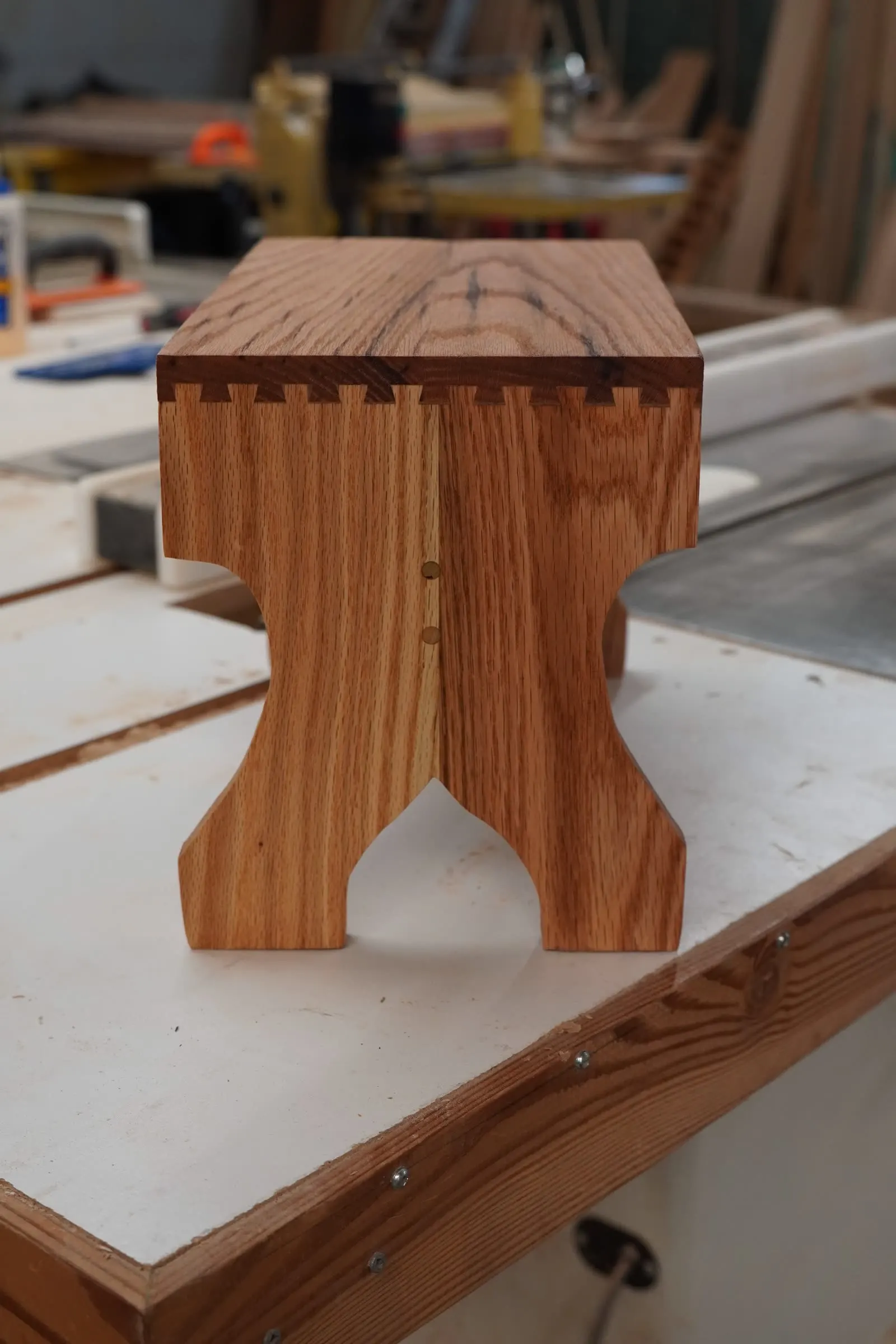 Hand-cut dovetail joinery along the top of a dark oak stool at Taylor & Grain