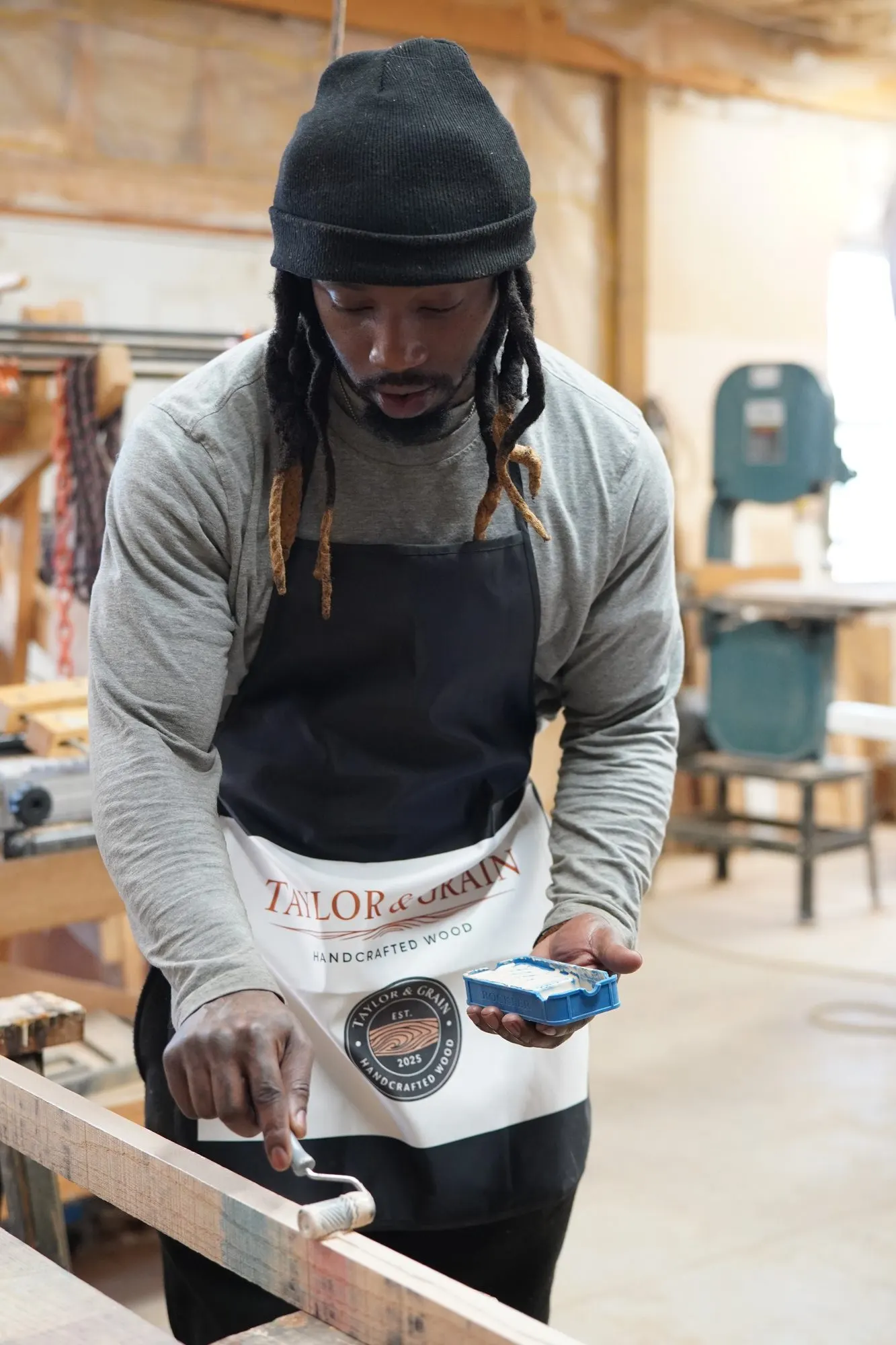Taylor and Grain maker rolling finish onto a hardwood board in the shop