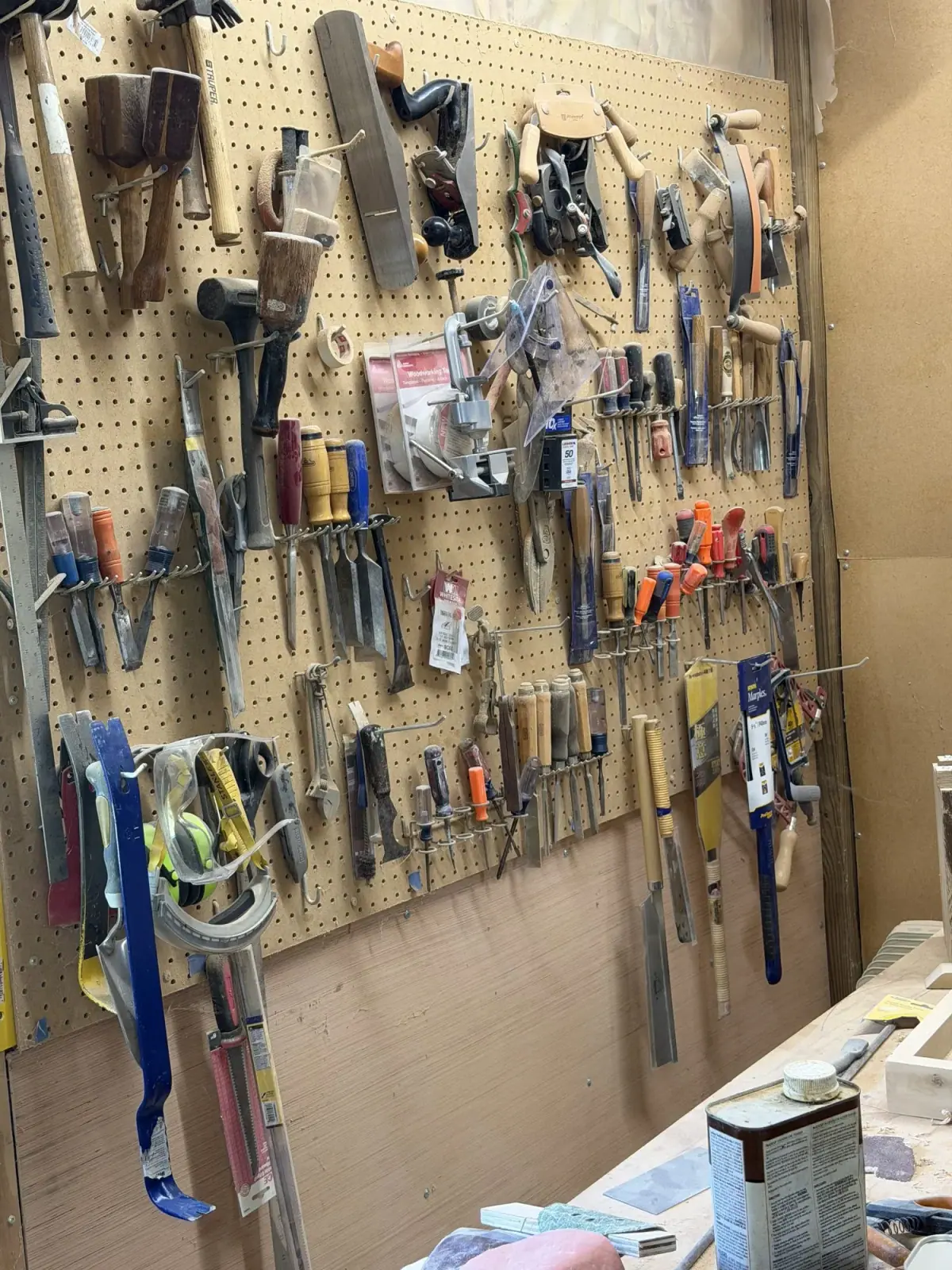 Pegboard wall of hand planes, chisels, saws, and clamps in the Taylor and Grain shop