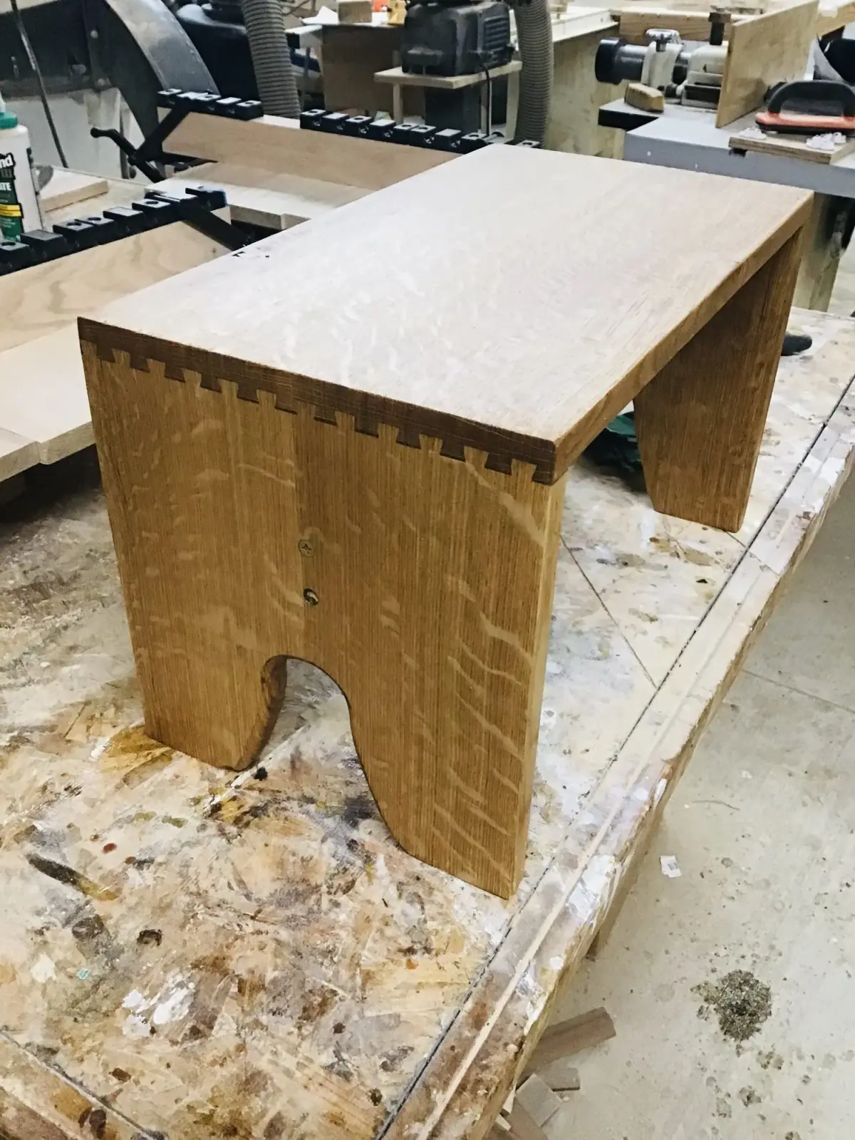 Unfinished oak stool with exposed box-joint corners on a worn workbench