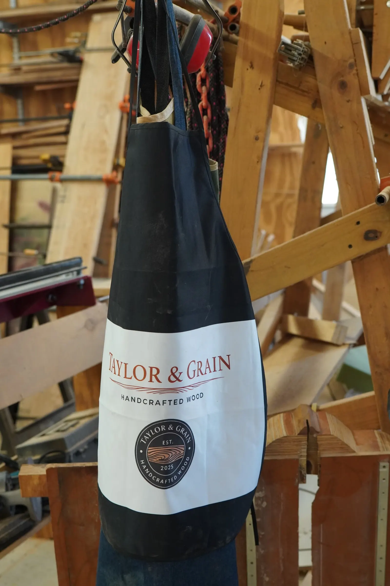 Taylor & Grain branded shop apron hanging in the woodworking shop