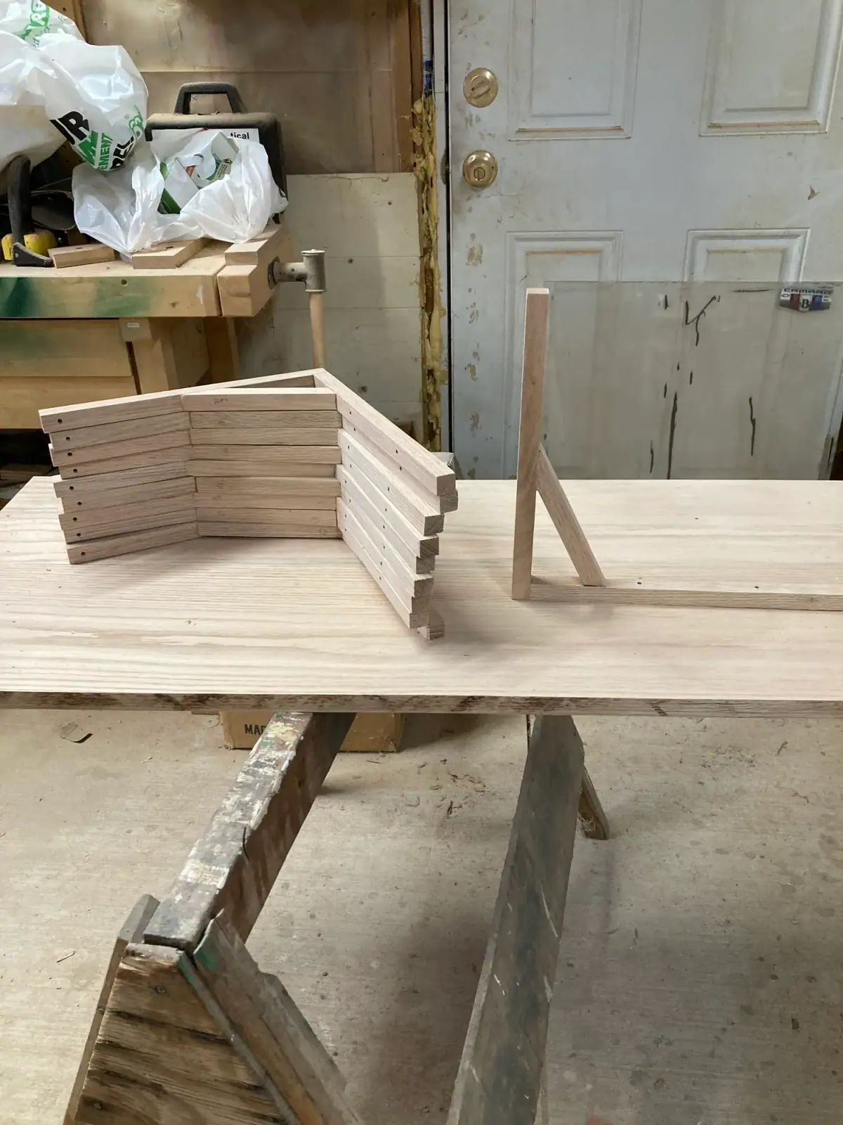 White oak shelf bracket standing on a workbench beside a stack of matching bracket parts